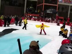 A man snowboarding in a chicken costume during a spring pond skim competition. - HD Stock Footage
