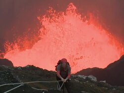 Man struggles with ropes whilst climb above erupting lava, Marum Volcano, Ambrym Island, Vanuatu Stock Footage