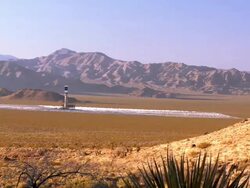 WS ZI solar thermal power plant with thousands of heliostat mirrors pointing at solar receiver boiler at top of power tower in Mojave Desert across from Nevada state line  / Ivanpah Dry Lake, California, USA Stock Footage