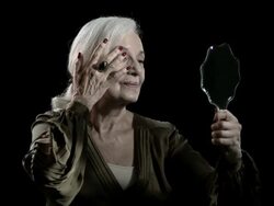Senior woman looking in mirror and adjusting appearance Stock Footage