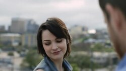 Young woman spins and throws her hands in the air overlooking city skyline Stock Footage