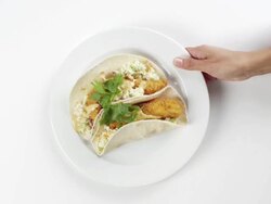 CU Woman hand entering setting down round white plate with two fish tacos / Omaha, Nebraska, United States Stock Footage
