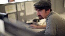 Trendy office worker in cubicle scans computer and types on keyboard Stock Footage