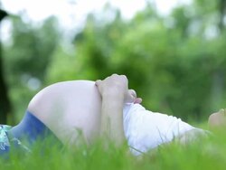 MS Pregnant woman lying in grass gently rubbing her abdomen / West Hurley, New York, United States Stock Footage
