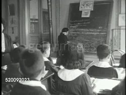 1946: REPUBLIC of TURKEY: PRIMARY SCHOOL: Angled WS BEHIND Children sitting in elementary school class w/ girl at blackboard, PAN Classroom, boys, girls in Peter Pan collar uniforms, VS Children at desks, MS Same girl wiring on board w/ chalk. Instructional Video