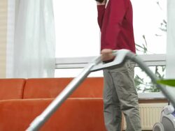 HD DOLLY: Boy Talking On Phone While Vacuuming Floor Stock Footage