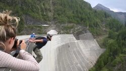 BASE jumper descends from high concrete dam to valley below Stock Footage