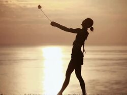 MS Sihouetted female poi dancer dancing in front of fiery sunrise sky and ocean / Montezuma, Costa Rica Stock Footage