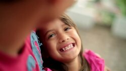 Young hispanic girl laughs in older brother's arms, gazes admiringly Stock Footage