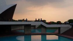 Visitors exiting the Lotus Temple, at dusk with reflections in the water body, in Delhi Stock Footage