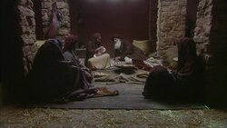 Virgin Mary sitting holding baby Jesus with Joseph and three wise men sitting nearby with stone walls and straw on floor Stock Footage