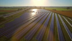Aerial of sun reflecting on panels of solar power station, LR pan Stock Footage