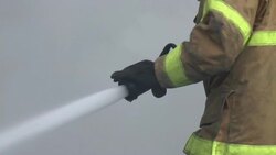 Firefighter sprays water while electrical line explodes overhead, slow motion,  2 clips Stock Footage