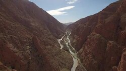Drone footage of woman looking at rocky mountains while sitting on retaining wall Stock Footage