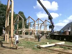WS Carpenters and crane operator slowly moving part of structure during framing of an energy efficient post / Grass Lake, Michigan, USA  Stock Footage
