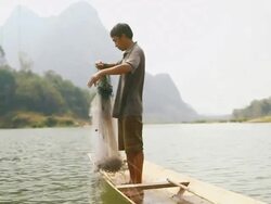 MS SLO MO Shot of small canoe moving and man putting fishing net into water / Ou river, Luang Prabang, Laos Stock Footage