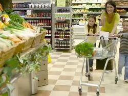 Mother and children in fruit and vegetable section of supermarket Stock Footage