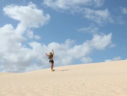 Teenage girl does cartwheels across sand dunes Stock Footage