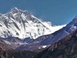 Panning shot of Time-lapse of the tip of Everest and surrounding peaks and trekkers on a foreground trail. Stock Footage