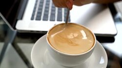Closeup of Latte Coffee art and woman hand typing on laptop keyboard Stock Footage