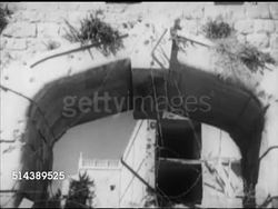 1952: JERUSALEM: PAN Barbed wire dividing Jerusalem into Arab 'Old City & Israel 'New City'. OLD CITY: Arab Legion guards patrolling top of building TD WS barbed wire over archway, VS Soldiers on wall as sentries watching 'No Man's Land' between two. Instructional Video