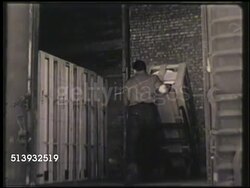 1951: EMPLOYEES: WAREHOUSE: VS Male worker using hand truck to move crate, another driving forklift w/ crate, another pushing refrigerator on moving dolly, in warehouse. Shipment, shipping, delivery, stock Instructional Video