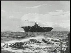 1942: BATTLE OF MIDWAY: MS U.S. Navy pilot in cockpit of flying aircraft. WS Silhouette of aircraft carrier at sea, Pacific Ocean. VS Various dive bomber aircrafts taking off from carrier flight deck, including Douglas SBD Dauntless dive bombers. WWII Instructional Video