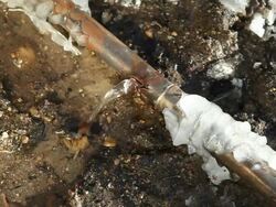 Frozen Cracked Copper Water Main Pipe Leaking Below Ground Stock Footage