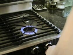 Woman lighting gas hob and putting kettle on Stock Footage