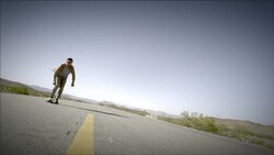 Young skater speeds up empty desert road on skateboard (slow-motion) Stock Footage