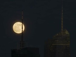 The moon rises behind a radio tower in NYC and the Bank of America Tower Stock Footage