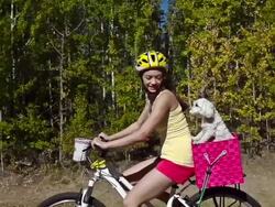 Young girl riding bicycle with pet dog Stock Footage