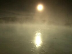 Wide Shot pan-left - Steam rolls off a pool at the Mammoth Hot Springs as the sun shines in the sky. / Wyoming, USA Stock Footage