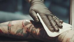 Tattoo artist tattooing young woman Stock Footage