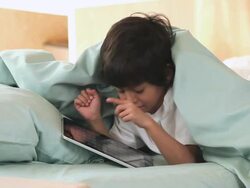 MS Child using tablet computer in bed / Richmond, Virginia, United States Stock Footage