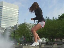 MS SLO MO Shot of young female jogger exercises by jumping up step at city fountain / Portland, Oregon, United States  Stock Footage