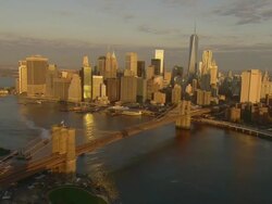 Aerial -Just after sunrise, flying south down the East River over the Manhattan and Brooklyn bridges while looking toward the lower Manhattan skyline including the Freedom Tower. Stock Footage