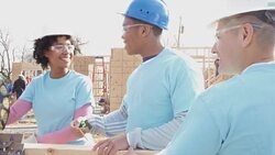 Volunteers use electric saw as they work on charity home Stock Footage