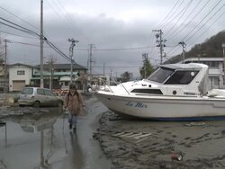Destruction caused by tsunami after magnitude 9 Tohoku earthquake, north east Japan, March 2011. Woman walks past boat washed onto street by tsunami in Ishinomaki City,  Miyagi Prefecture Stock Footage