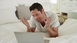 Smiling man laying on bed videoconferencing with laptop Stock Footage