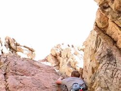 Tilt shot of of a male rock-climber going up a cliff-face. Stock Footage