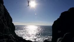 Man traverses highline stretched above sea below Stock Footage