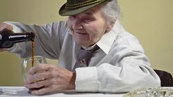 Elderly woman opens bottle of dark beer. Stock Footage