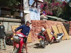 MS PAN Boy trying to start his motorcycle while another boy goes to get his behind panels of cassava crackers drying in sun / Luang Prabang, Laos Stock Footage