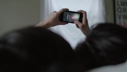 Two girls lying in bed scroll through photos on smartphone Stock Footage