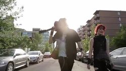 Cool young couple with guitar walking down sunny urban street Stock Footage