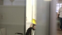 Young businesswoman speaks in meeting, opens folder; office worker with coffee mug stops in doorway to chat (dolly shot) Stock Footage