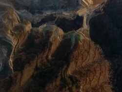 High Angle aerial tracking,right , Red, rippled gorges surround a coal strip mine operation. / West Virginia Stock Footage