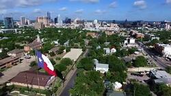 Aerial: Over Austin Texas Capital Cities with Texas Flag with Skyline Cityscape background with Frost Bank Tower and Austonian Stock Footage