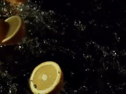 Orange double falling in to water, black background Stock Footage